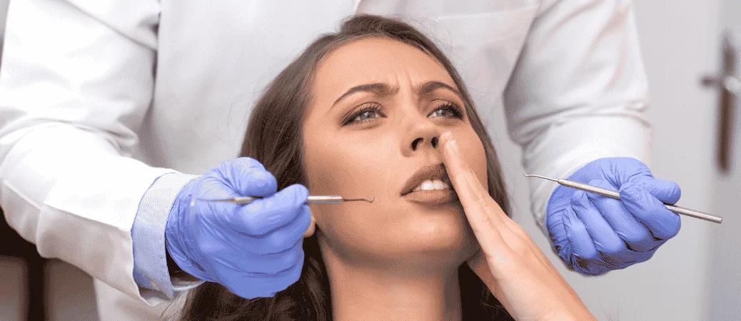 Woman holding her jaw while a dentist examines her