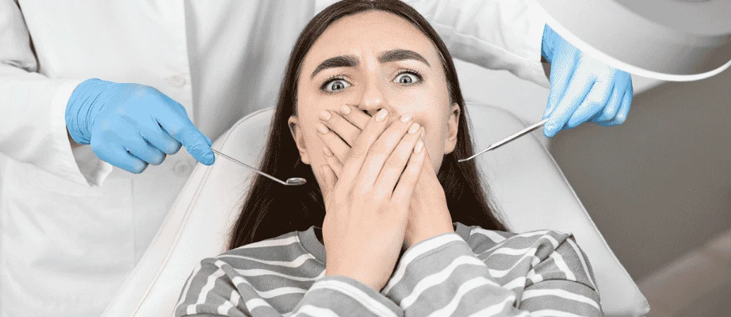 Anxious patient covering her mouth in the dental chair